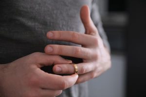 Focus on man's hands removing wedding band as he contemplates getting divorced