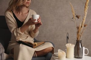 Self-reflection can help healing after divorce-woman sitting alone with cup of coffee, candles and journal in slef-reflection.